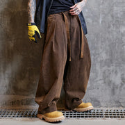 Person wearing brown wide-leg pants and yellow work boots against a gray concrete wall.