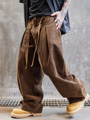 Person wearing brown wide-leg pants and yellow boots against a gray concrete wall.