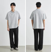 Person wearing a gray polo shirt and black pants, shown from front and back views.