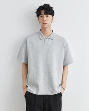 Man wearing a gray polo shirt against a white background