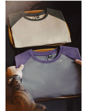 Gray and purple shirt with a brand logo on a dark background