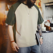 Man wearing a green and beige baseball shirt in a kitchen setting