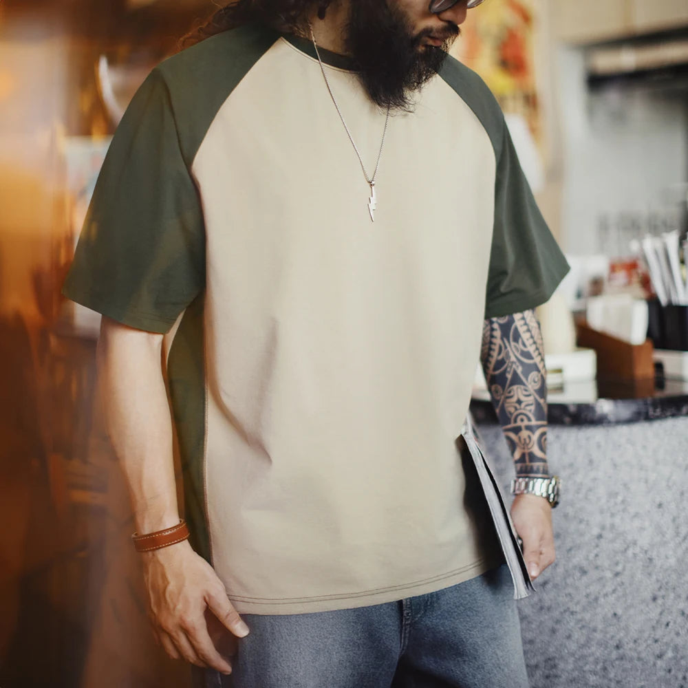 Man wearing a green and beige baseball shirt in a kitchen setting