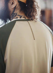 Person wearing a beige and green sports shirt with a tattoo on the neck.