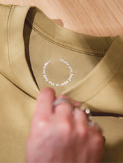 Close-up of a beige shirt with a brand logo on a wooden surface