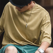 Person wearing a beige long-sleeve shirt and green shorts with a blurred background