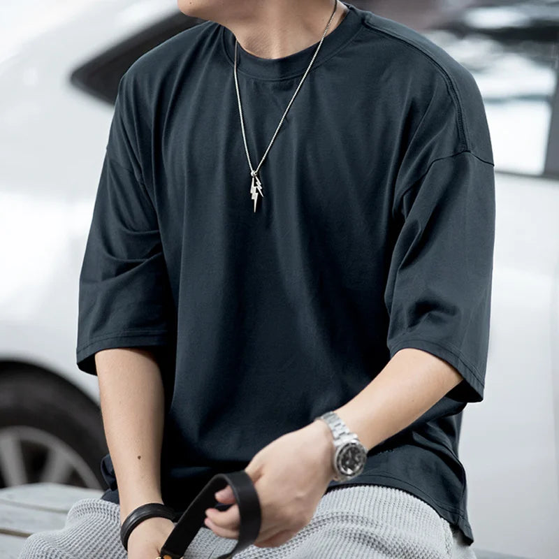 Person wearing a dark gray t-shirt with a blurred background