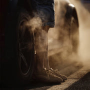 Person wearing shorts and sneakers standing next to a tire with smoke in the background