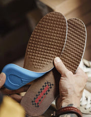 Brown shoe insole with textured bottom held by a hand, with text '2 comfortable bottom, no hard support'.