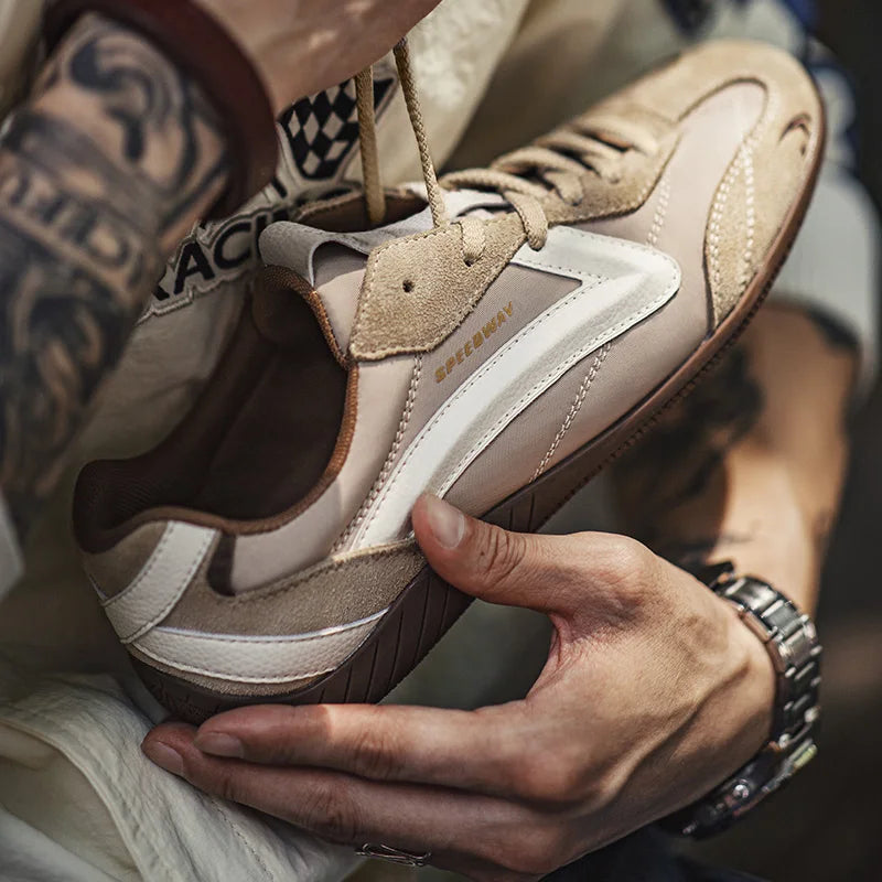 Close-up of a person holding a brown and beige sneaker with visible brand logo.