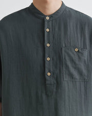 Dark gray shirt with button details on a plain background