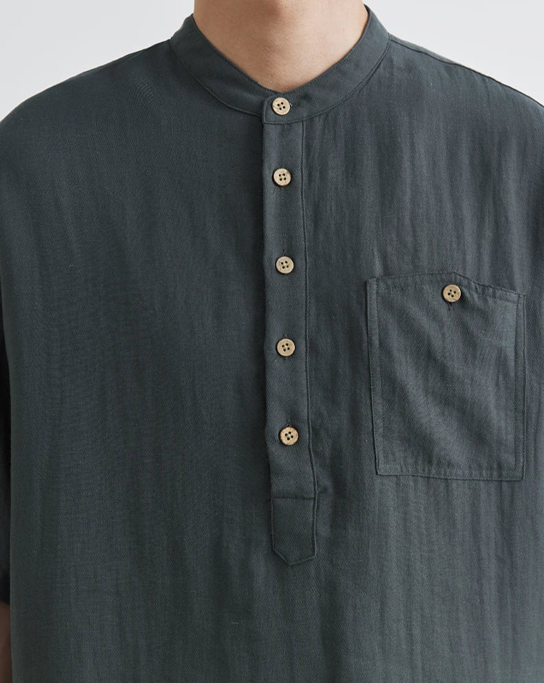 Dark gray shirt with button details on a plain background