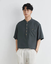 Man wearing a dark gray short-sleeve shirt with buttons on a white background