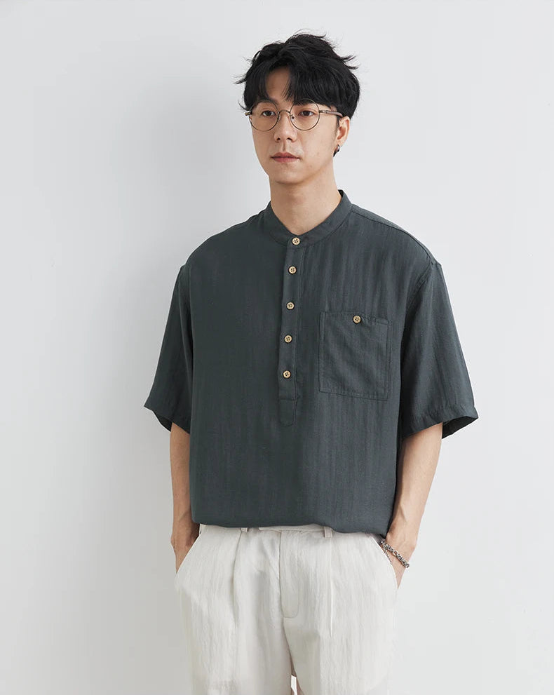 Man wearing a dark gray short-sleeve shirt with buttons on a white background