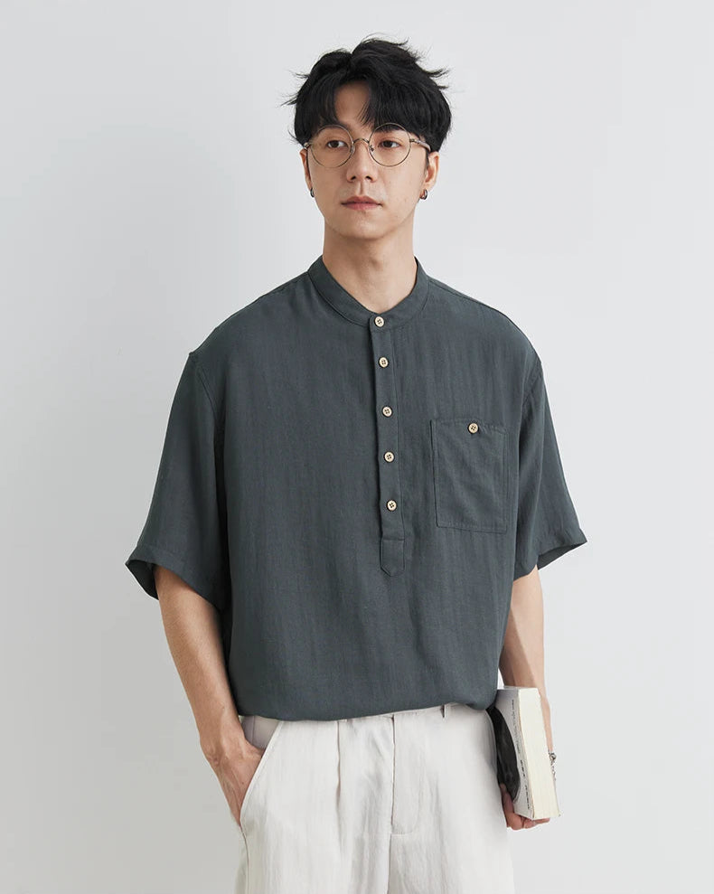 Man wearing a dark gray short-sleeve shirt with buttons on a light gray background