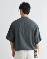 Person wearing a dark green shirt from behind on a light gray background