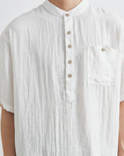 White textured shirt with buttons and a pocket on a plain background