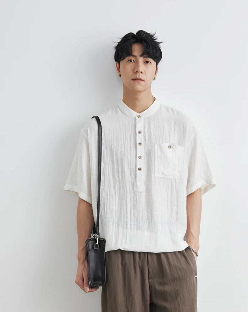 Man wearing a white shirt and brown pants holding a black bag against a white background