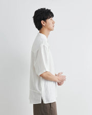 Person wearing a white shirt and brown pants against a light gray background