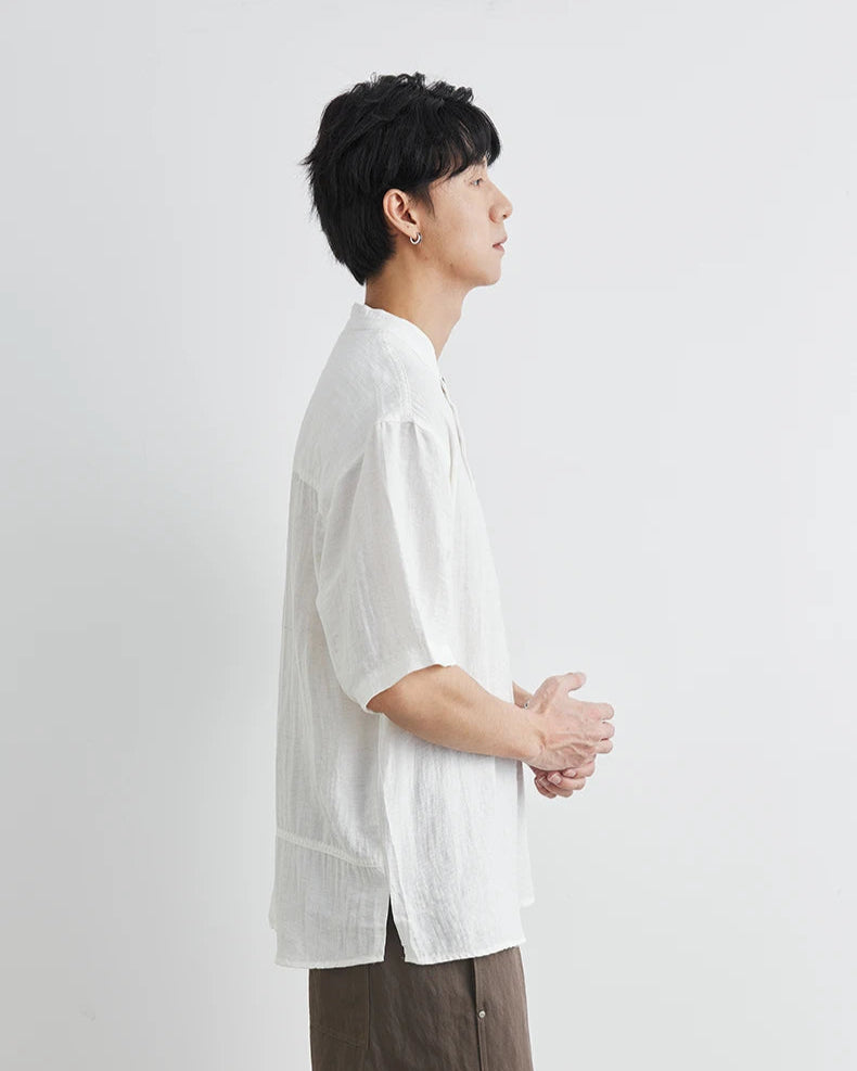 Person wearing a white shirt and brown pants against a light gray background