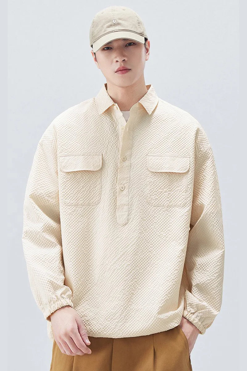 Person wearing a textured beige shirt and cap on a plain background