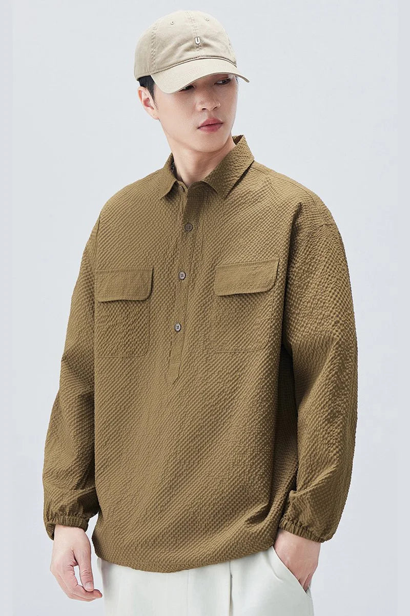 Person wearing a brown textured shirt and beige cap on a white background