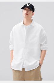 Person wearing a white shirt and beige pants with a black cap on a gray background