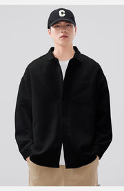 Person wearing a black jacket, white shirt, beige pants, and black cap with a white 'C' on a light gray background