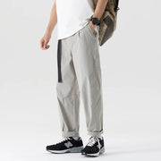 Person wearing light gray pants with black accents on a white background