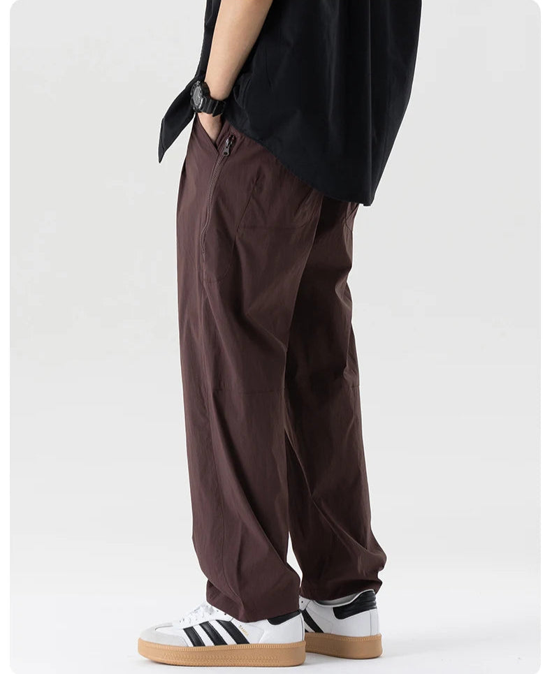 Person wearing brown pants and white sneakers with black stripes on a white background