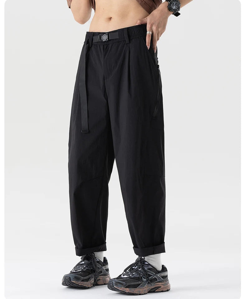 Person wearing black high-waisted pants with a belt on a white background