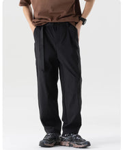 Person wearing black pants and a brown shirt on a white background