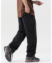 Person wearing black pants and brown shoes on a white background