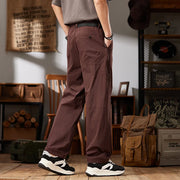 Person wearing brown pants standing in a room with wooden floor and rustic decor.