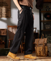 Person wearing black workwear casual pants with yellow boots in a room setting.