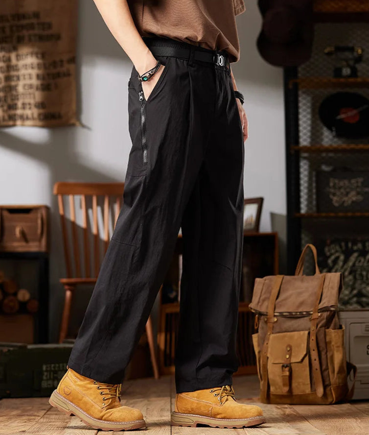 Person wearing black workwear casual pants with yellow boots in a room setting.