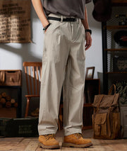 Person wearing beige workwear casual pants in a rustic setting with 'Worldwide' branding.