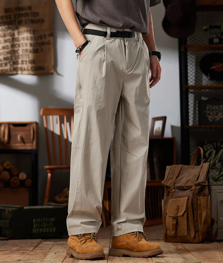 Person wearing beige workwear casual pants in a rustic setting with 'Worldwide' branding.