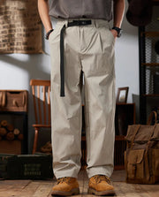 Person wearing beige cargo pants with a belt, standing in a rustic indoor setting.