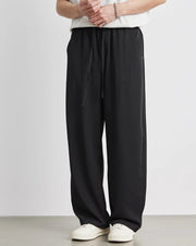Person wearing black pants and white shoes on a plain background