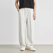 Person wearing white wide-leg pants and a black top on a plain background