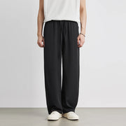 Person wearing black wide-leg pants and a white top on a plain background