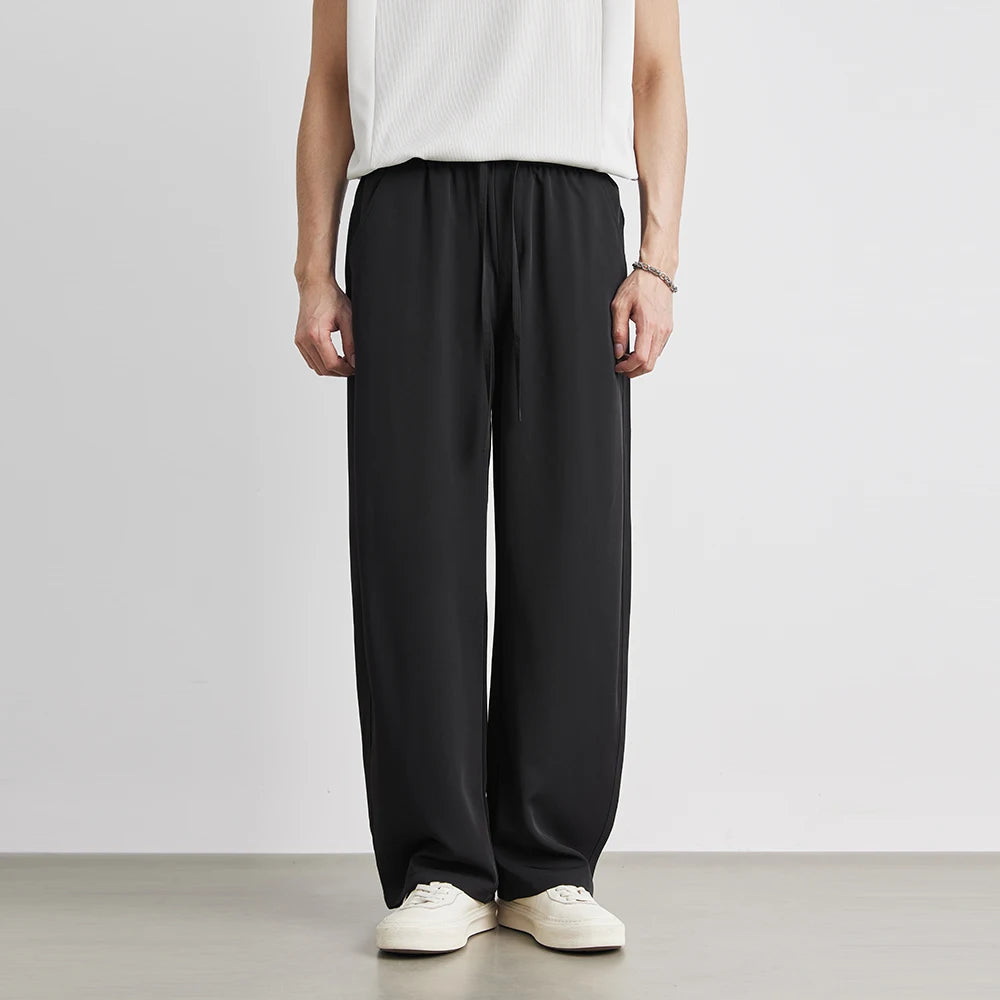 Person wearing black wide-leg pants and a white top on a plain background