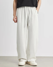 Person wearing light-colored wide-leg pants and white shoes on a plain background