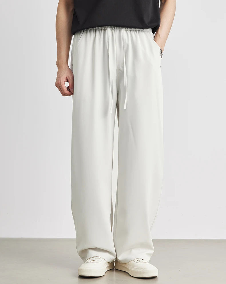 Person wearing light-colored wide-leg pants and white shoes on a plain background