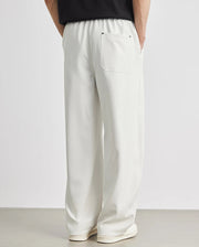 White pants worn by a person on a plain background
