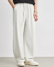 Person wearing white wide-leg pants and a black top on a plain background