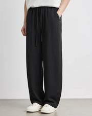 Person wearing black wide-leg pants and white sneakers on a plain background