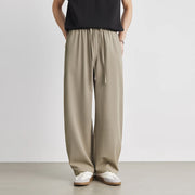 Person wearing beige wide-leg pants and a black top on a plain background