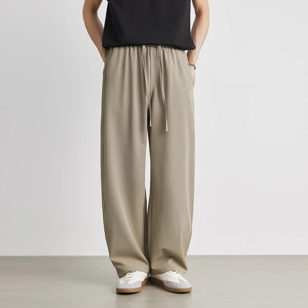 Person wearing beige wide-leg pants and a black top on a plain background